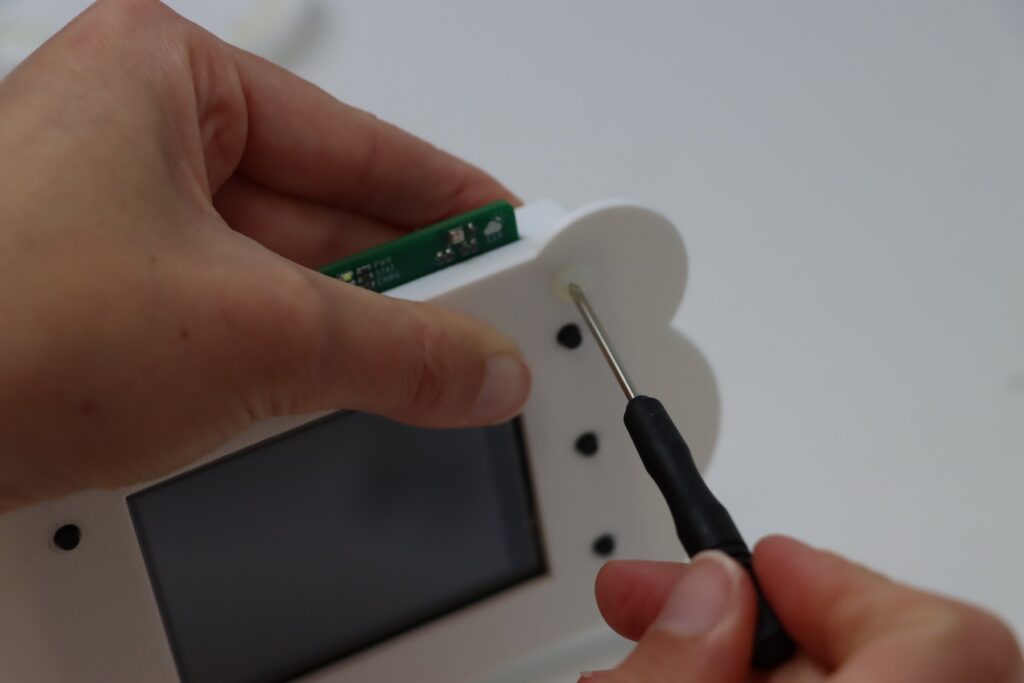 Student hands assembling the Climate Cadet weather monitor with a screwdriver